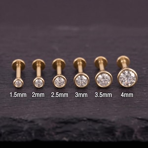 以下が含まれることがあります： 1.5mmから4mmまでサイズ順に並べられた、ベゼルセッティングの透明な丸い石が付いた6つのゴールドトーンのスタッドピアス。各ピアスはストレートポストと円形のフェイスを備えており、それぞれのサイズが各ピースの下にラベル付けされています。