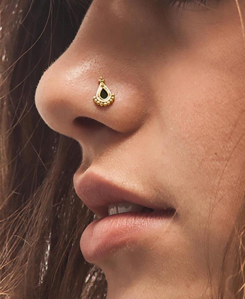Solid 14k Gold Nose Stud: A close-up of a person's face, focusing on their nose and mouth area.
