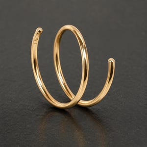 A gold-colored ring with a twisted design, resting on a dark surface.