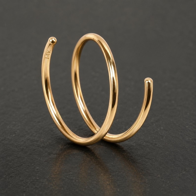 A gold-colored ring with a twisted design, resting on a dark surface.