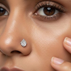 Dainty White Gold Nose Stud: A close-up of a woman's face, with her eyes closed and her hands covering her ears.