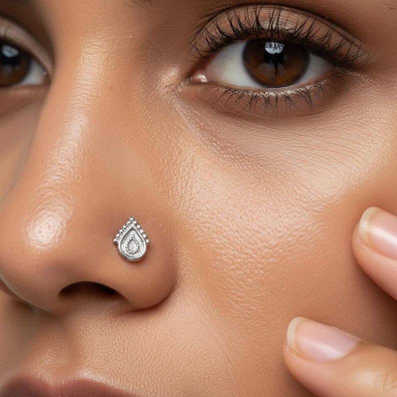 Dainty White Gold Nose Stud: A close-up of a woman's face, with her eyes closed and her hands covering her ears.