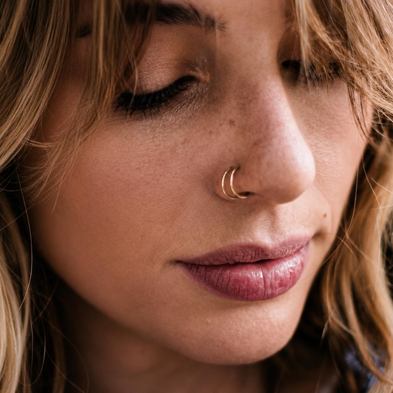 A close-up of a woman's face, focusing on her nose and lips, with her eyes closed.