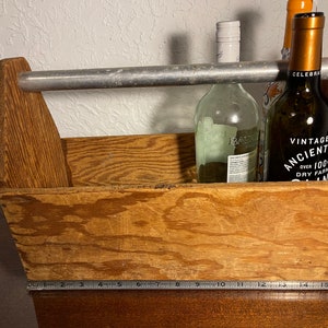 Peut inclure: Une caisse en bois avec une poignée en métal, contenant trois bouteilles de vin en verre. Les bouteilles sont étiquetées "Celebrate", "Bazan" et "Vintage 1991 Ancient Hill Dry Farm Wine".