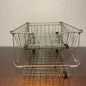May include: Two stacked silver wire mesh letter trays. The trays are empty and have a rectangular shape.