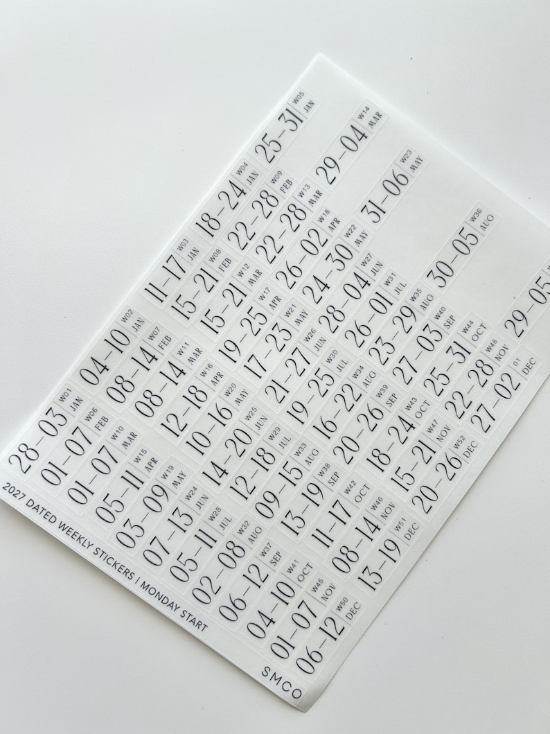 May include: A sheet of white planner stickers featuring black text for the year 2027. The stickers list weekly date ranges with Monday starts, week numbers from W01 to W52, and month abbreviations. The text 2027 DATED WEEKLY STICKERS | MONDAY START and SMCO are printed on the sheet.