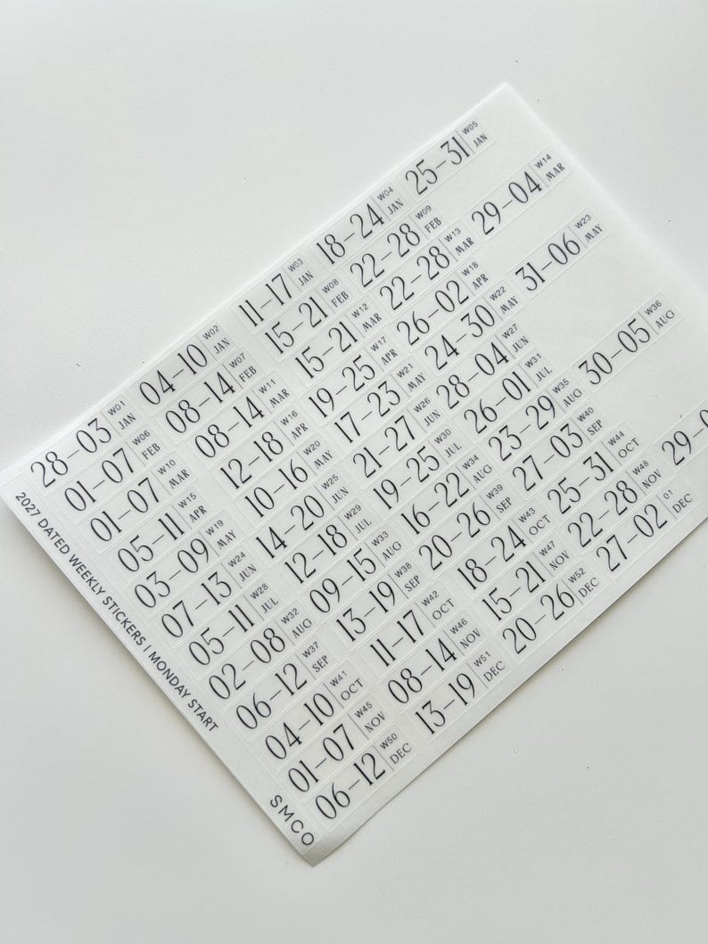 May include: A sheet of clear adhesive stickers featuring black text for the 2027 calendar year. The stickers are organized by week, displaying date ranges, week numbers, and month abbreviations, with a Monday start format and SMCO branding.