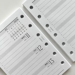 May include: Two white planner pages with gray horizontal lines and pre-punched holes. One page shows a May 2026 calendar and the date May 11. The other page shows the dates May 12 and May 13. The words "Stylish Minimal" are printed on the pages.