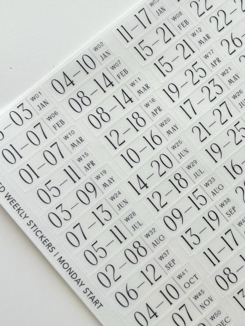 May include: A sheet of clear adhesive weekly stickers featuring black printed text. Each sticker displays a date range, a week number, and a month abbreviation. The text reads WEEKLY STICKERS | MONDAY START, followed by a sequence of dates from January to December.