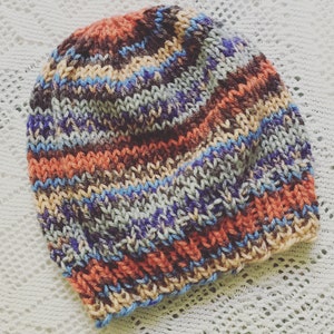 May include: A colourful knitted hat with stripes of orange, brown, blue and grey.