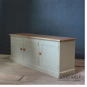 May include: A light green cabinet with three doors and wooden knobs. The cabinet has a wood top and sits on a wooden floor. The text "THE GOOD SHELF COMPANY" is visible on the floor.