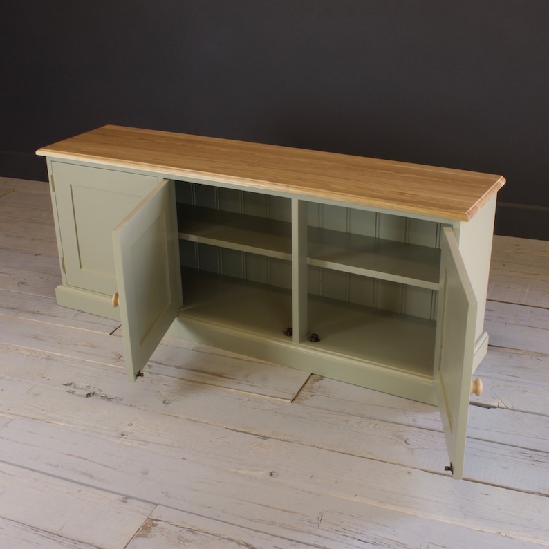May include: A light green wooden cabinet with two doors and three shelves. The doors are open and the shelves are empty. The cabinet has a wood top.
