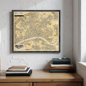 May include: Framed vintage map of Cologne, Germany, in sepia tones. The map, titled "Plan von Köln," features detailed street layouts, the Rhine River, and surrounding areas. The map is encased in a dark wooden frame, adding a classic touch to the artwork.