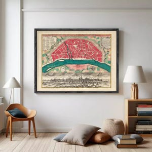 May include: Framed vintage map print featuring a detailed city plan in red, green, and beige tones. The map depicts a city with a river running through it, and is framed in a black wooden frame. A decorative piece for home decor.