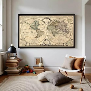 May include: A framed vintage world map with a black border. The map features detailed illustrations of continents and oceans in shades of beige, green, and brown. The map is displayed on a white wall above a white chair with pillows.