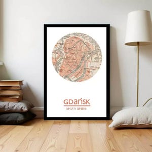 Könnte beinhalten: Gerahmter Druck mit einer kreisförmigen Karte von Gdańsk, Polen, in Pfirsich- und Beigetönen. Der Name der Stadt und die Koordinaten sind darunter gedruckt. Der Druck befindet sich vor einem weißen Hintergrund in einem schwarzen Rahmen.