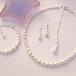 May include: A pearl necklace, bracelet, and earrings set. The necklace and bracelet are made of white pearls and silver chain. The earrings are silver with white pearl drops.