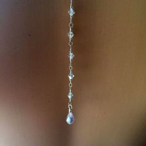 May include: A silver chain with clear crystal beads and a teardrop-shaped crystal pendant.