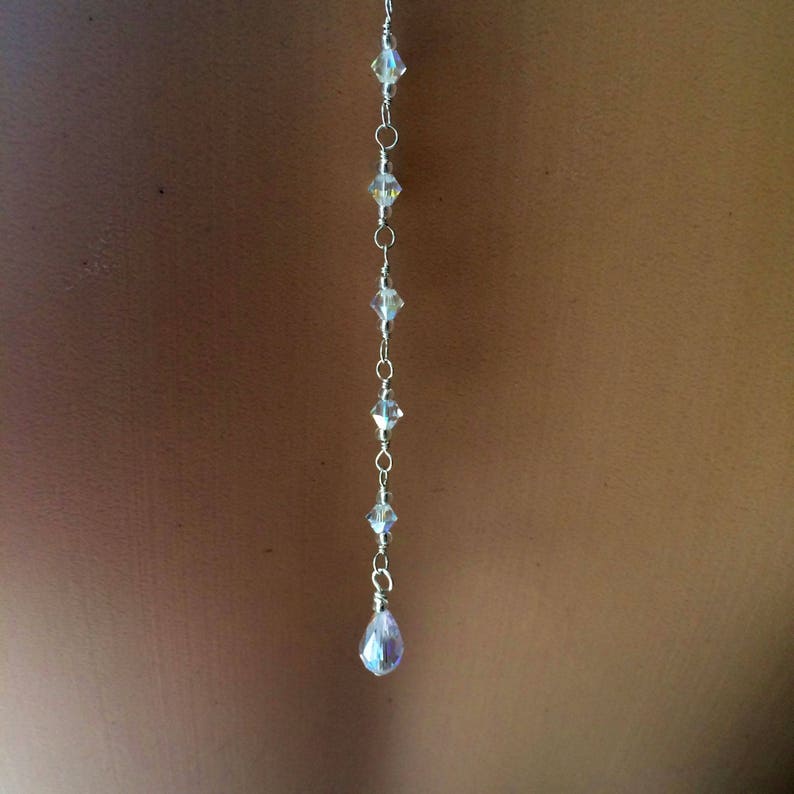 May include: A silver chain with clear crystal beads and a teardrop-shaped crystal pendant.