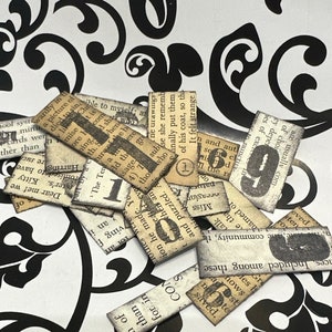 May include: A collection of vintage paper scraps with black ink printed text and numbers. The paper scraps are arranged on a black and white patterned surface.