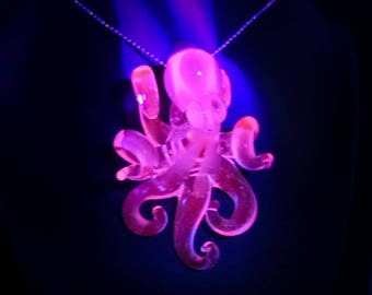 May include: A pink glass octopus pendant necklace glows under a black light. The octopus has eight tentacles and is detailed with a textured surface.