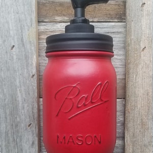 May include: Red glass mason jar with a black pump dispenser and the words "Ball Mason" embossed on the front.