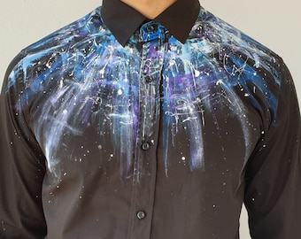 Peut inclure: Une chemise boutonnée à manches longues noire avec un motif abstrait de peinture éclaboussée blanche, bleue et violette sur le devant.