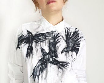 Peut inclure: Chemise boutonnée blanche avec un motif abstrait noir et blanc de corbeaux en vol.
