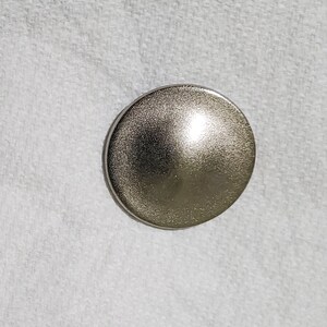 May include: A silver-toned, round, dome-shaped button.