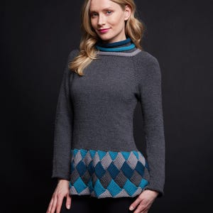 May include: A gray knit sweater with a high neck and long sleeves. The sweater features a geometric pattern in shades of gray and blue at the waist. The neckline has a blue and gray trim.
