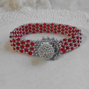 May include: A red and silver beaded bracelet with a silver clasp. The bracelet is made with small, round beads and has a checkered pattern.