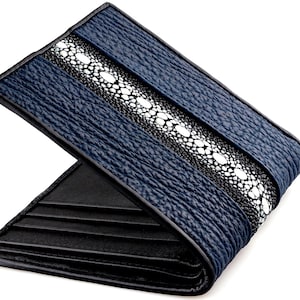 Puede incluir: Una cartera de cuero azul con una incrustación de piel de raya negra y blanca. La cartera está cerrada y la incrustación es visible en la parte delantera.