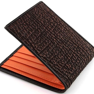 May include: A brown leather wallet with an orange interior. The wallet has a textured exterior and multiple card slots.