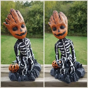 May include: A Halloween-themed figurine of a skeletal figure with a pumpkin head. The figure is holding a small pumpkin in its hand. The figure is standing on a base that resembles dirt.