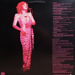 May include: A woman with red hair sings into a microphone. The album cover features the song titles "Skylark", "Drinking Again", "Breaking Up Somebody's Home", "Surabaya Johnny", "I Shall Be Released", "Optimistic Voices", "Lullaby of Broadway", "In the Mood", "Da Doo Run Run", "Twisted", "Higher & Higher (Your Love Keeps Lifting Me)".