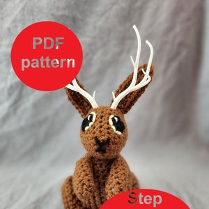 Könnte beinhalten: Ein braunes Häkelkaninchen mit weißen Geweih. Das Kaninchen sitzt mit gekreuzten Beinen. Das Bild enthält den Text "PDF pattern" und "Step by step instructions".
