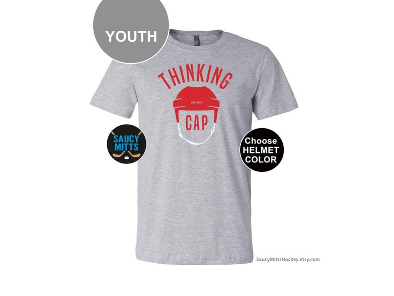 May include: Gray youth t-shirt with the text "Thinking Cap" and a hockey helmet graphic. The helmet is red. The text "Choose Helmet Color" is on a black circle. The text "Saucy Mitts" is on a blue circle with a hockey stick graphic.