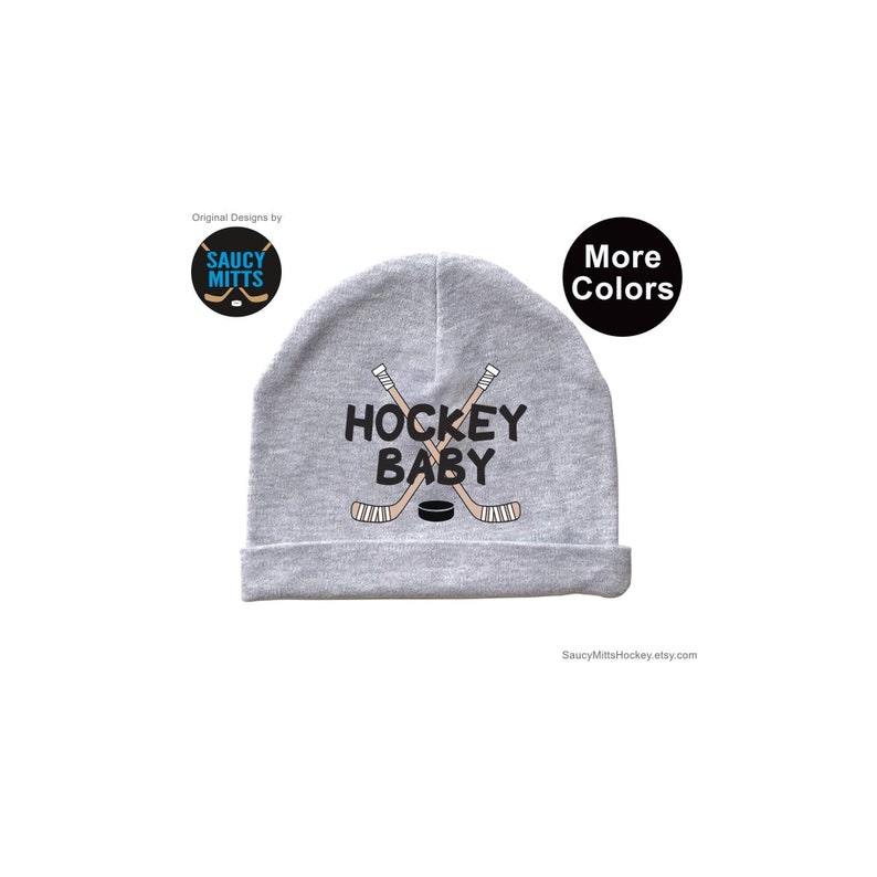 May include: Gray baby beanie with the text "Hockey Baby" and a graphic of two crossed hockey sticks and a puck.