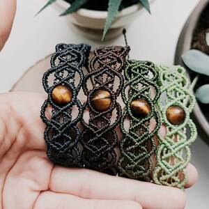 May include: Four macrame bracelets with tiger's eye beads. The bracelets are in shades of black, brown, green, and light green.