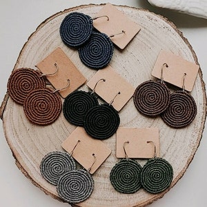 Puede incluir: Seis pares de pendientes hechos a mano con un diseño en espiral. Los pendientes están hechos de cordón tejido y están disponibles en una variedad de colores, incluyendo marrón, negro, gris y verde.