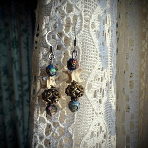 May include: A pair of silver earrings with bone-shaped charms, multi-colored glass beads, and ornate metal accents.