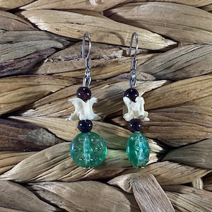 May include: A pair of earrings with a green glass bead, a white bone bead, and a dark red bead on each earring.