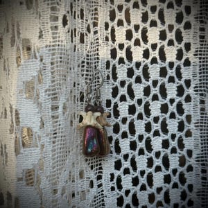 Peut inclure: Une paire de boucles d'oreilles avec des perles de verre irisées et des breloques en forme d'os suspendues à des crochets argentés.