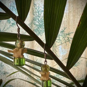 May include: A pair of earrings with a white bone-shaped charm, green glass beads, and silver hooks.