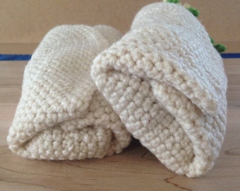 May include: Two crocheted white fabric pouches, one slightly larger than the other, are folded and placed side by side on a wooden surface.