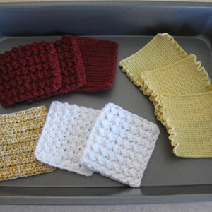 May include: A collection of crocheted squares in various colors, including yellow, white, and burgundy, displayed on a baking sheet. The squares are made with different stitch patterns and textures.