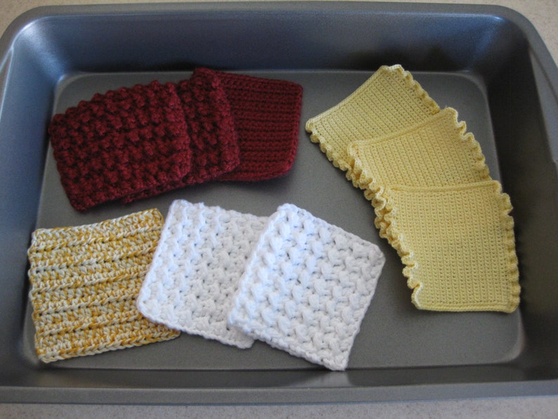 May include: A collection of crocheted squares in various colors, including yellow, white, and burgundy, displayed on a baking sheet. The squares are made with different stitch patterns and textures.