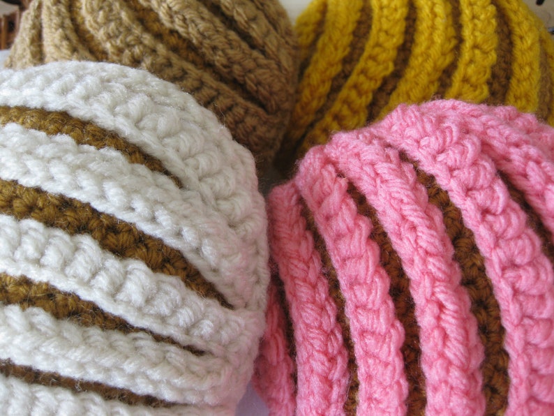 May include: Three crocheted striped balls in brown, white, yellow, and pink. The balls are made with a textured yarn and have a striped pattern.