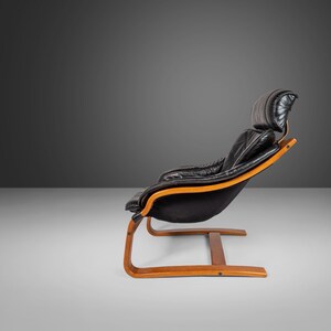 May include: A black leather armchair with a wooden frame and a curved base. The chair has a high back and a comfortable, padded seat.