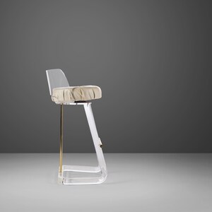 May include: A clear acrylic bar stool with a beige upholstered seat and a gold metal base.